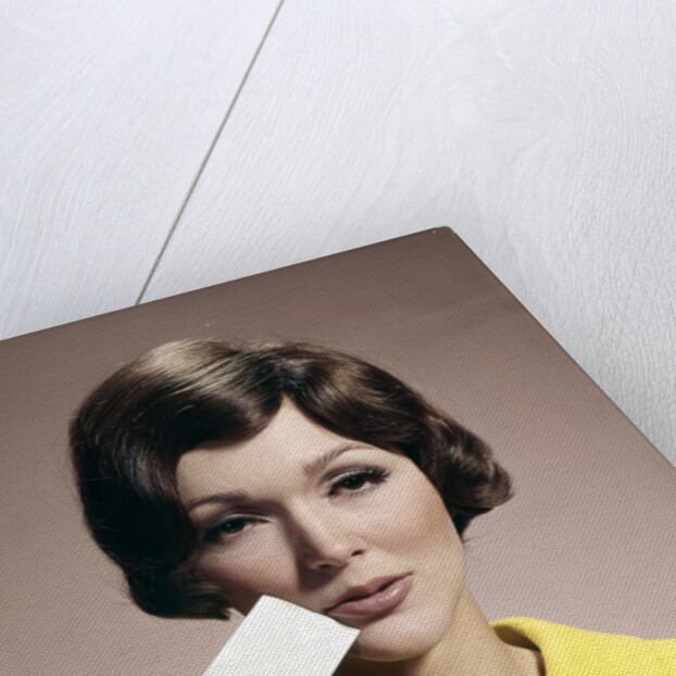 1960s Brunette Woman Holding Blank Business Card To Face Looking At Camera Wearing Yellow Top by Anonymous