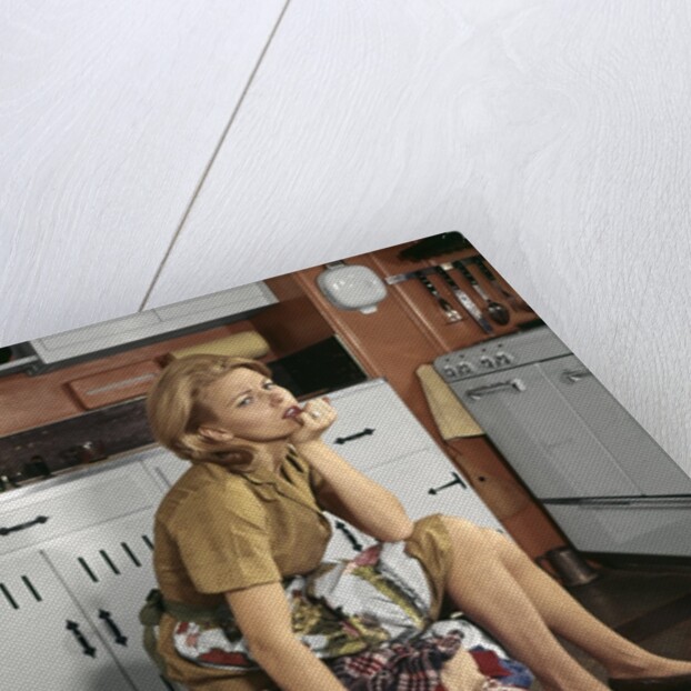 1960s Tired Housewife Sitting On Top Of Laundry Basket In Kitchen by Anonymous