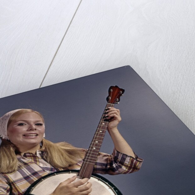 1960s Young Blonde Woman Wearing Plaid Shirt Playing Banjo Singing Folk Music Looking At Camera by Anonymous