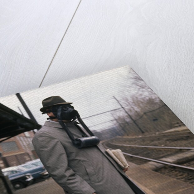 1950s Man Wearing Gas Mask Hat At Commuter Train Station Holding Briefcase Newspaper by Anonymous