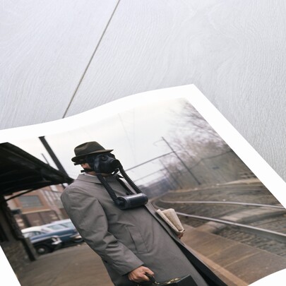 1950s Man Wearing Gas Mask Hat At Commuter Train Station Holding Briefcase Newspaper by Anonymous