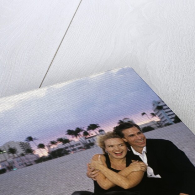 1990s Laughing Couple Man Woman In Formal Wear Sitting Hugging On Beach by Anonymous