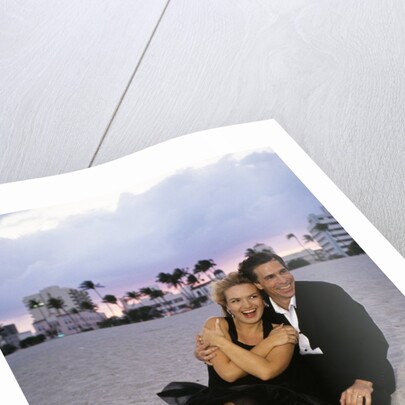 1990s Laughing Couple Man Woman In Formal Wear Sitting Hugging On Beach by Anonymous