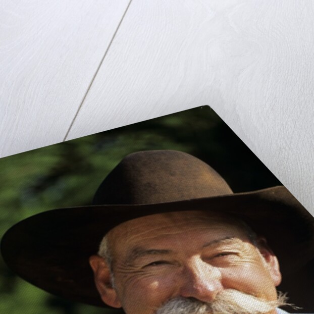 1990s Portrait Of Smiling Cowboy With Gray Mustache Black Hat Blue Shirt Looking At Camera by Corbis