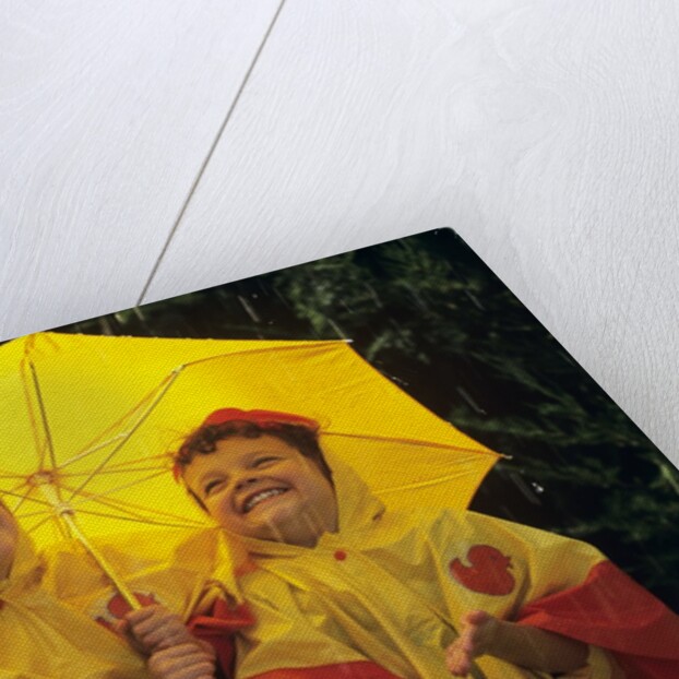 1990s Two Laughing Young Girls Holding A Yellow Umbrella And Wearing Yellow Rain Ponchos by Anonymous