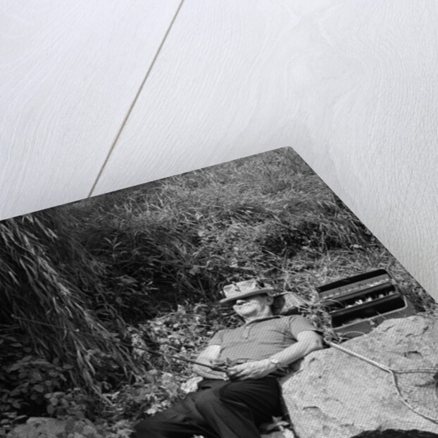 1950s Lazy Fisherman Lying Back On Rock With Hat Pulled Over Eyes Fishing In Creek by Anonymous