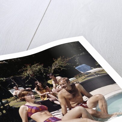 1960s Four People On Patio Couple Man Woman Sitting On Edge Of Swimming Pool by Anonymous
