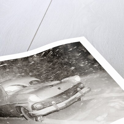 1950s Snow Covered Automobile Driving On Road In Deepening Winter Blizzard Snow by Anonymous