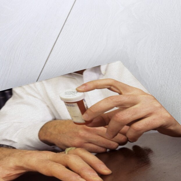 1990s Doctor Writing Refill Prescription For Patient Holding Pill Bottle by Anonymous