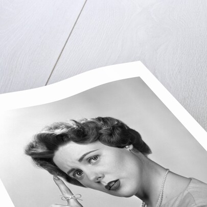 1950s Concerned Woman With Reminder String Knot Tied On Finger Of Hand To Help Remember Something Looking At Camera by Anonymous