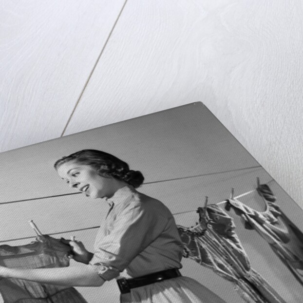 1950s Smiling Woman Housewife Hanging Wash Child Dress On Clothesline To Dry by Anonymous