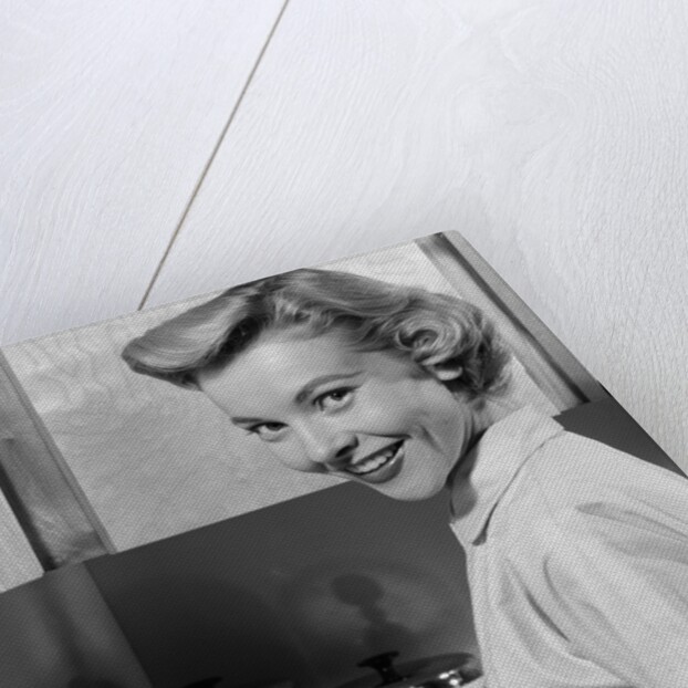 1950s Smiling Blonds Woman Mother Warming A Baby Bottle Of Milk In Kitchen Looking At Camera by Anonymous