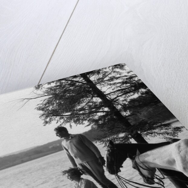 1930s Man Standing On Rock Lakeside Holding Reins Of Two Horses With Woman Seated Beside Looking Off To Side by Anonymous