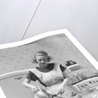 1930s Woman In Kitchen Wearing Apron Making Breakfast Pouring Water Into Coffee Pot by Anonymous