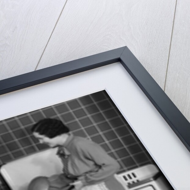 1930s Woman Housewife And Friend Wearing Apron Cooking Food In Kitchen On Gas Stove Indoor by Anonymous