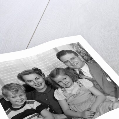 1940s 1950s Portrait Of Smiling Family Man Woman Boy Girl Sitting On Sofa Looking At Camera by Anonymous