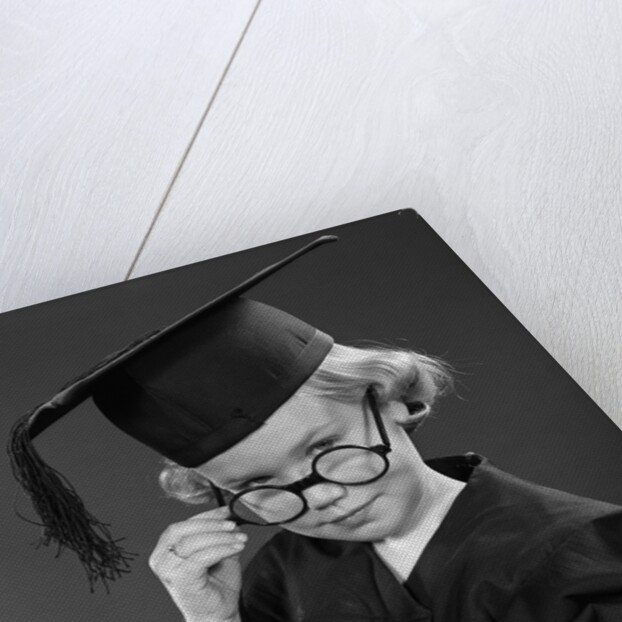 1950s Little Blond Girl Wearing Scholarly Glasses Graduation Cap And Gown Looking At Camera by Anonymous