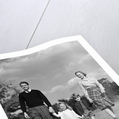 1940s Family Father Mother Son Daughter Holding Hands Together Walking On Grass by Anonymous