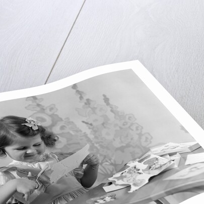 1940s Smiling Little Girl Cutting Paper With Scissors by Anonymous