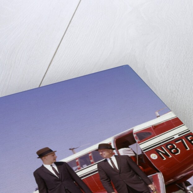 1960s Two Businessmen In Suits And Hats Carrying Briefcases Walking From A Small Twin Prop Business Airplane Talking by Anonymous