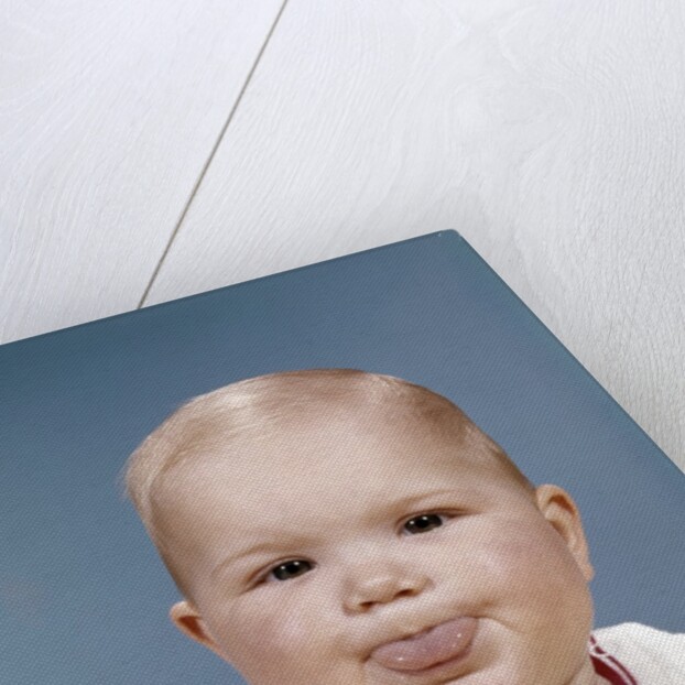 1960s Portrait Of Cute Blond Chubby Baby Looking At Camera Sticking Out Tongue by Anonymous