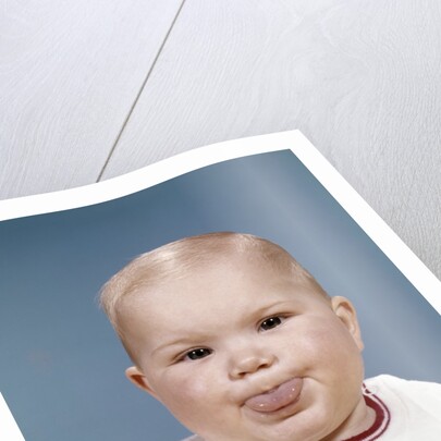 1960s Portrait Of Cute Blond Chubby Baby Looking At Camera Sticking Out Tongue by Anonymous