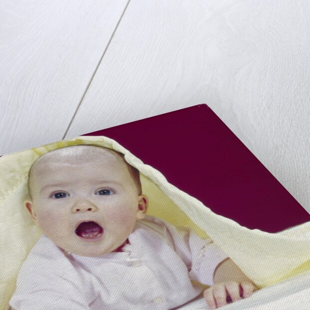 1960s Baby Mouth Wide Open Peeking Out From Under Yellow Blanket Looking At Camera by Anonymous