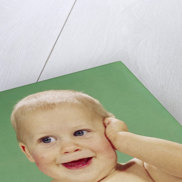 1960s Smiling Happy Baby Looking Off To The Side With Hand Touching Face by Anonymous