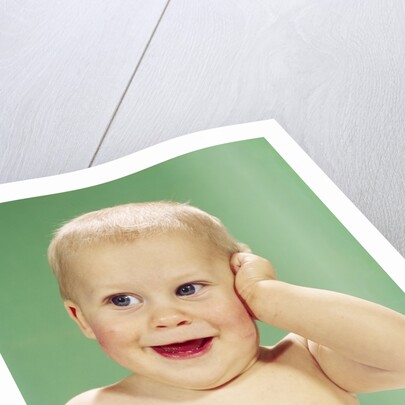 1960s Smiling Happy Baby Looking Off To The Side With Hand Touching Face by Anonymous