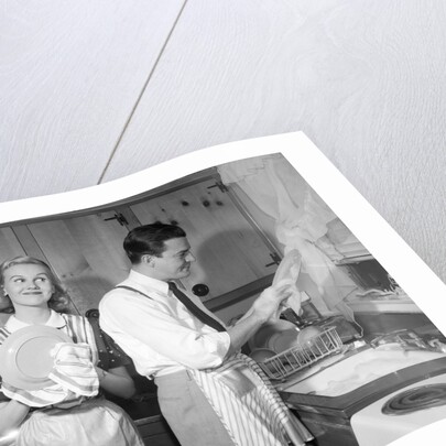 1950s smiling couple washing the dishes together by Anonymous