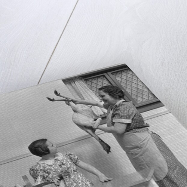 1940s housewife in kitchen showing plucked turkey to children by Anonymous