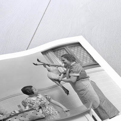1940s housewife in kitchen showing plucked turkey to children by Anonymous