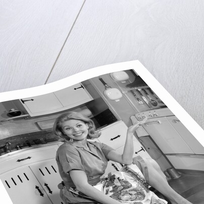 1960s smiling housewife sitting on full laundry basket by Anonymous