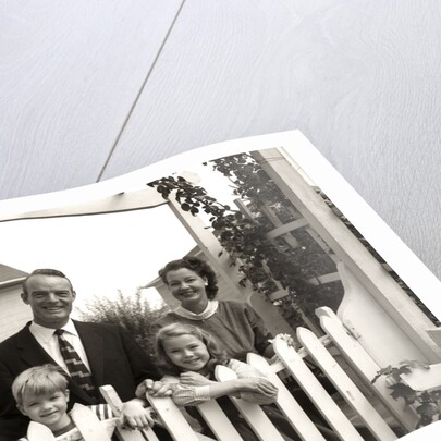 1950s family of four behind picket fence by Anonymous