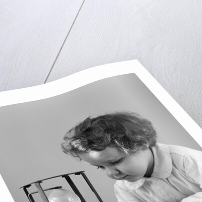 1940s young girl leaning on table staring at hourglass by Anonymous