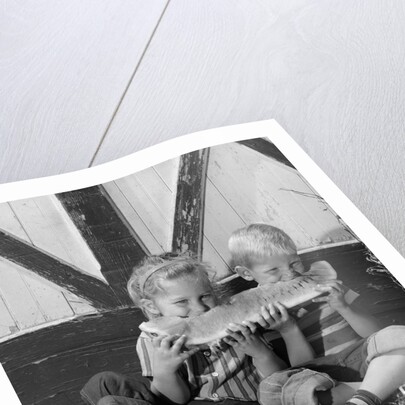 1960s boy and girl sharing a slice of watermelon by Anonymous