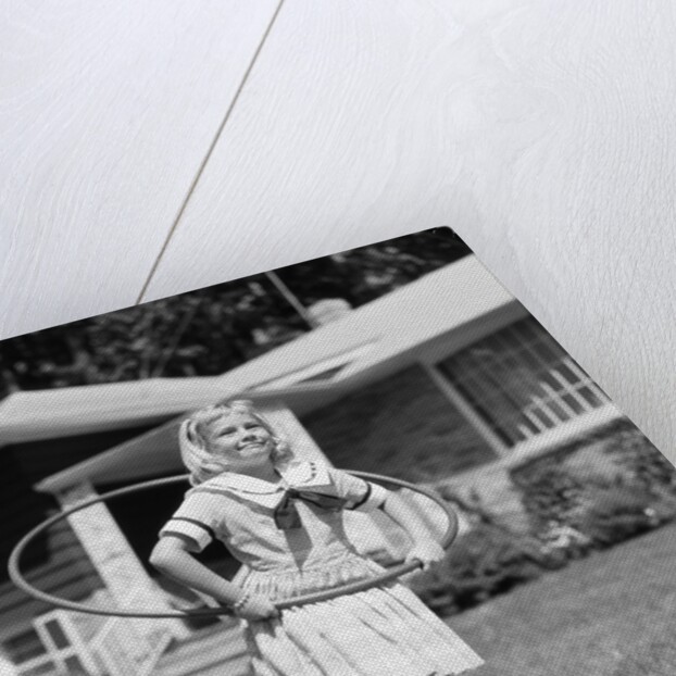 1950s girl on suburban sidewalk playing with a hula hoop by Anonymous