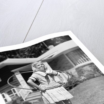 1950s girl on suburban sidewalk playing with a hula hoop by Anonymous