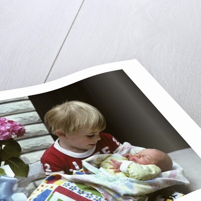 1970s boy holding a newborn baby by Anonymous