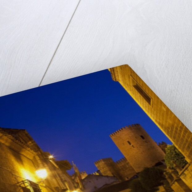 Streets of Banos de la Encina at night with the Moorish castle, named Burgalimar Castle, in the back by Anonymous