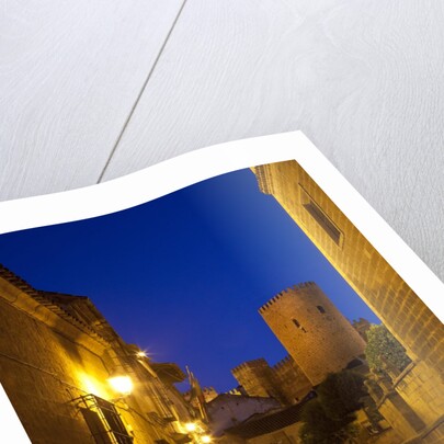 Streets of Banos de la Encina at night with the Moorish castle, named Burgalimar Castle, in the back by Anonymous