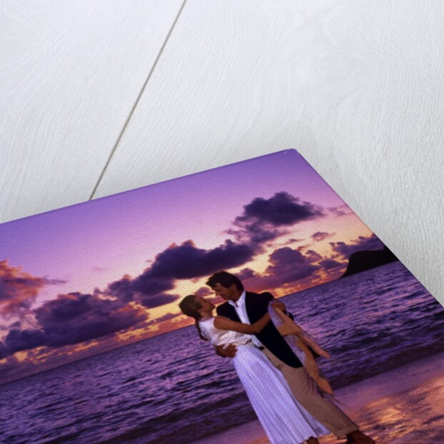Dressed up couple embracing on the beach at sunset by Anonymous