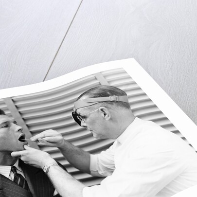 1930s 1940s doctor examining throat of a young man by Anonymous
