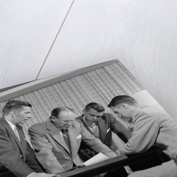 1950s group of businessmen looking at a blueprint on a table by Anonymous