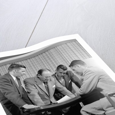 1950s group of businessmen looking at a blueprint on a table by Anonymous