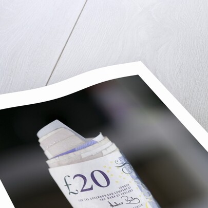 A roll of twenty pound notes on a table by Anonymous