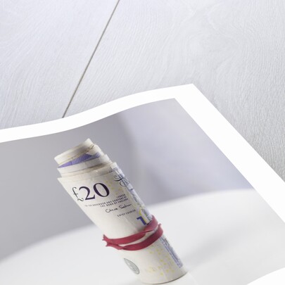 A roll of twenty pound notes on a table by Anonymous