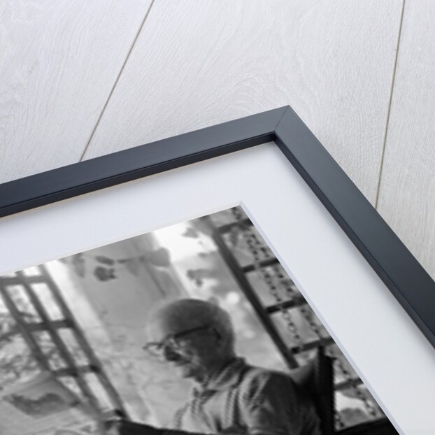 1970s elderly man reading newspaper on porch in a rocker by Anonymous