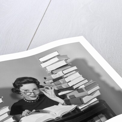 1950s portrait of woman sitting with stacks of books by Anonymous