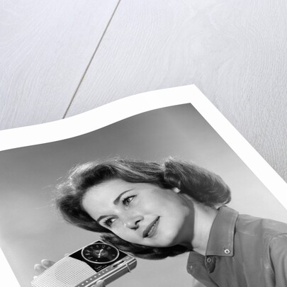 1960s smiling teenage girl listening to portable radio by Anonymous
